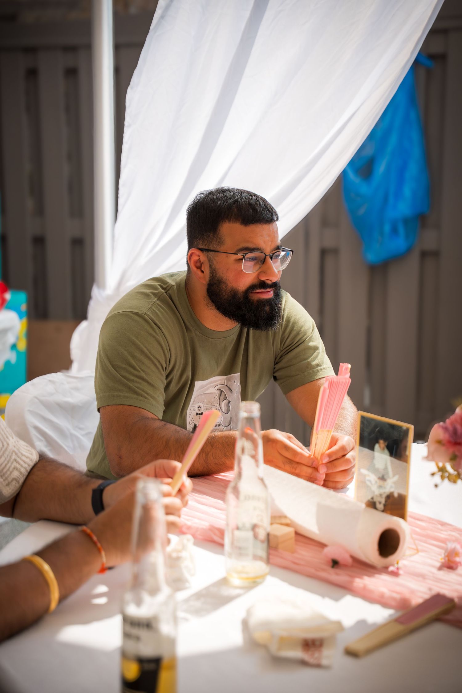 Person in olive t-shirt sitting at table with drinks and party decorations.