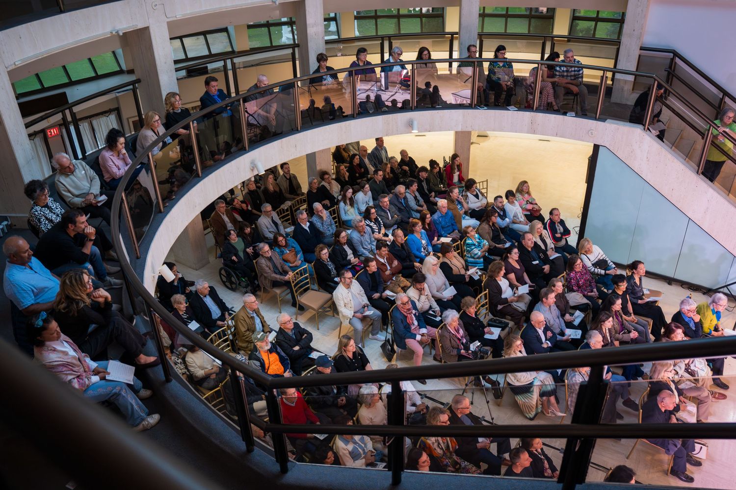 Aerial view of a large crowd gathered in a modern multi-level atrium venue for an indoor event.