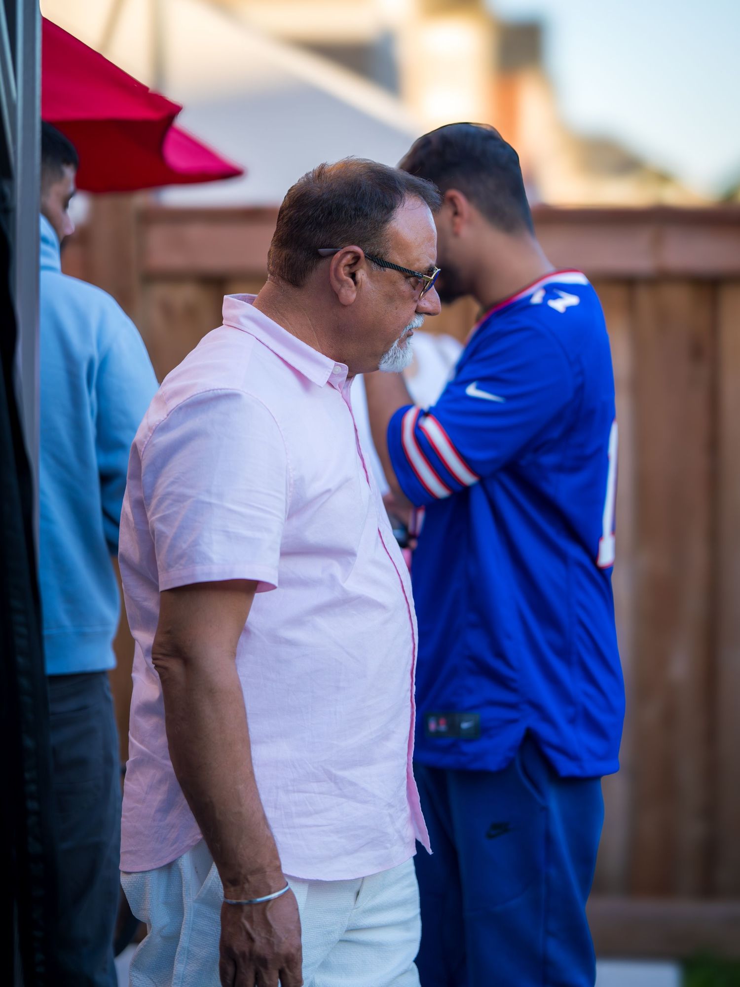 Two men in casual attire having a conversation at an outdoor backyard celebration event.