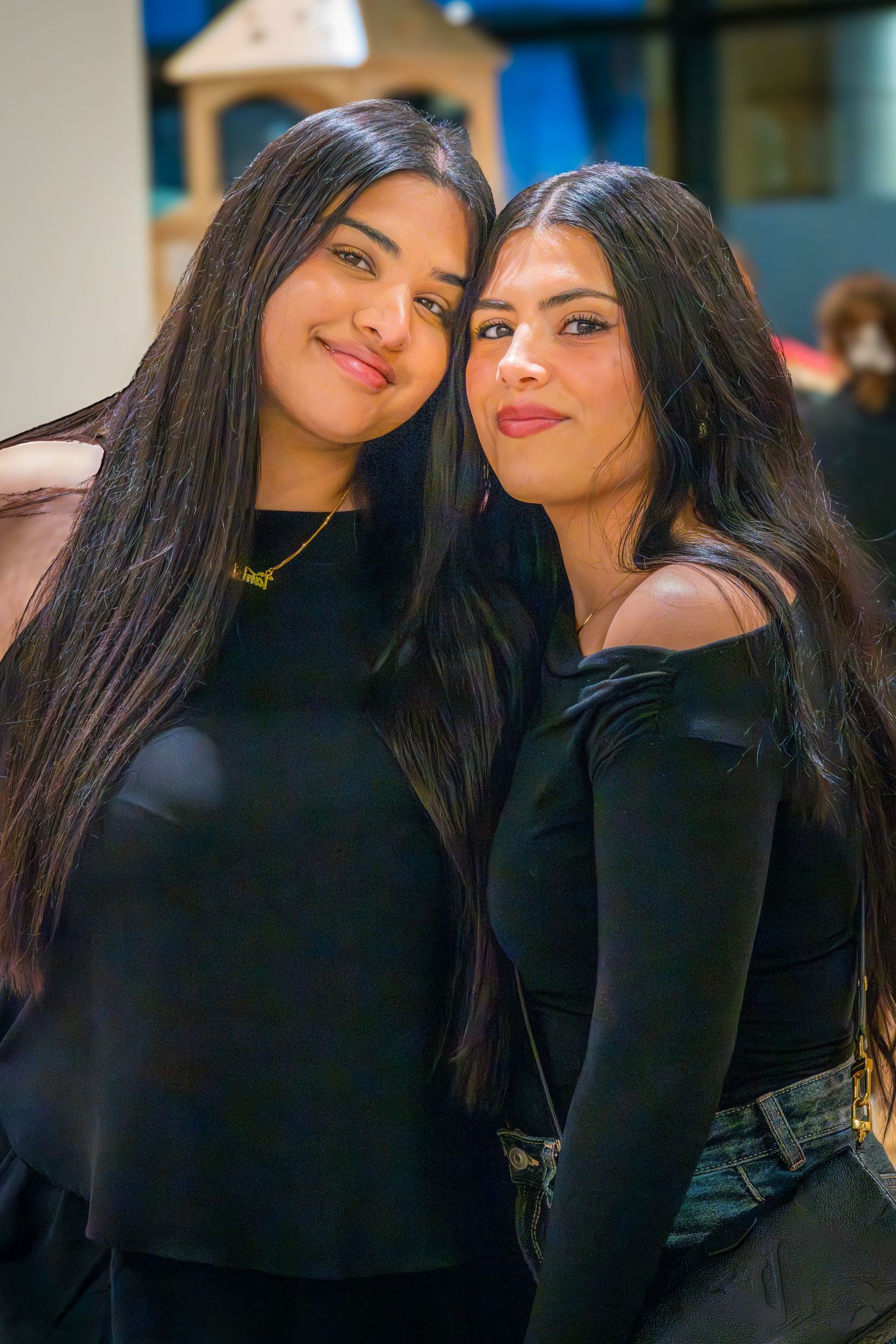Two young women in black outfits posing together at an indoor play center.