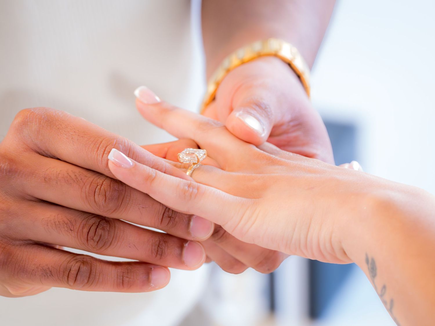 Close-up of a man sliding a gold diamond engagement ring onto a woman's finger.