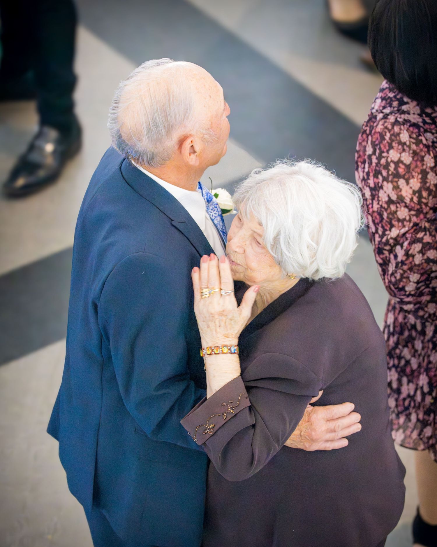 Elderly couple sharing a tender embrace and kiss at a formal anniversary celebration event.