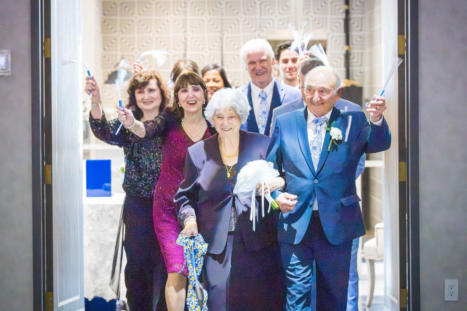 Smiling group of guests celebrating and waving at a formal anniversary party entrance.