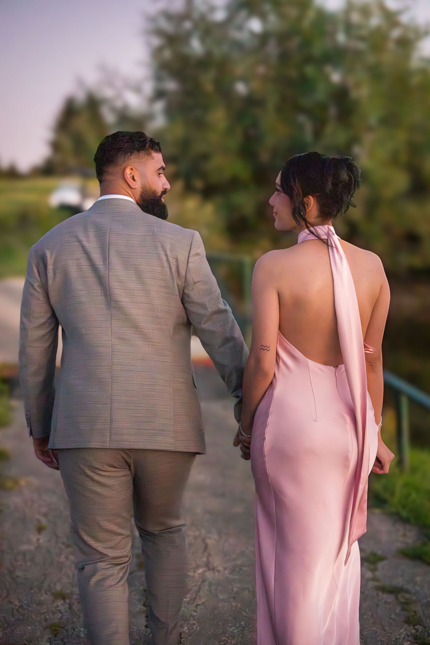 Back view of couple walking together on outdoor path at dusk.