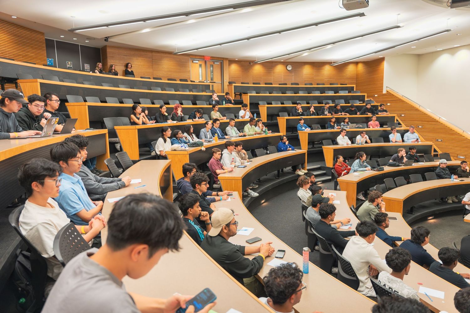 Students seated in a tiered lecture hall during an academic presentation or seminar.