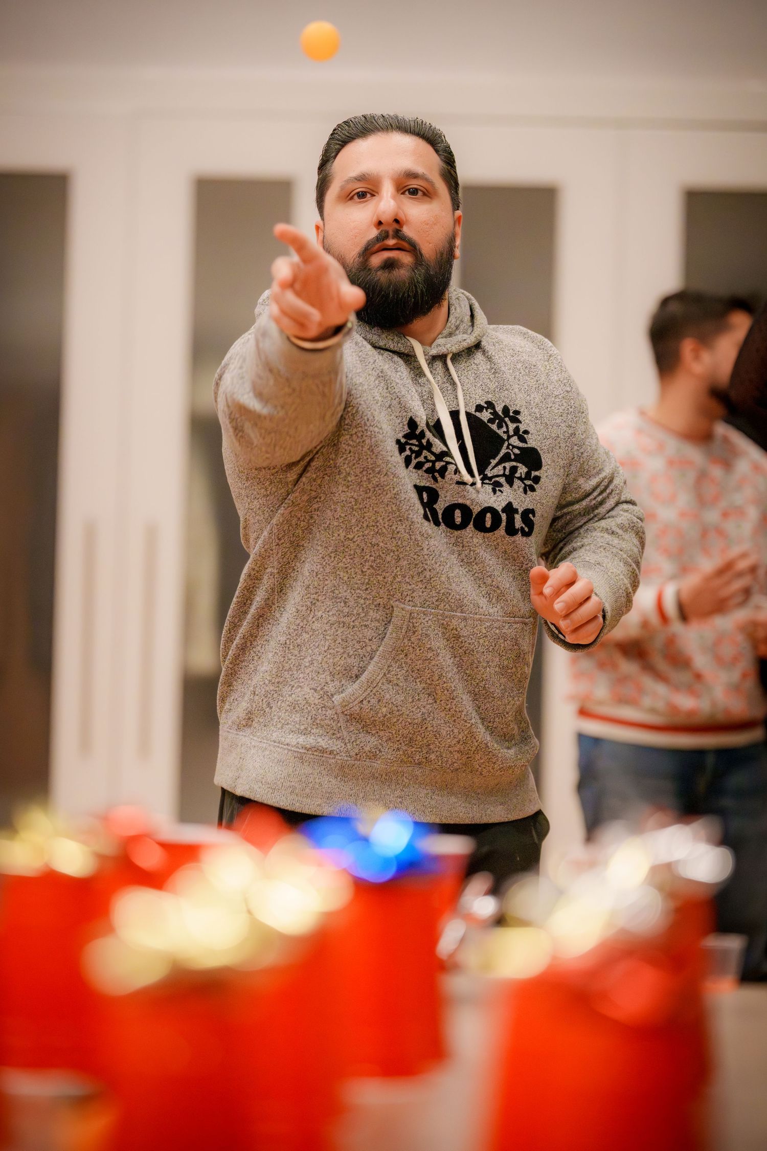 Person in a gray hoodie playing a game with flying orange and red lights in the background.