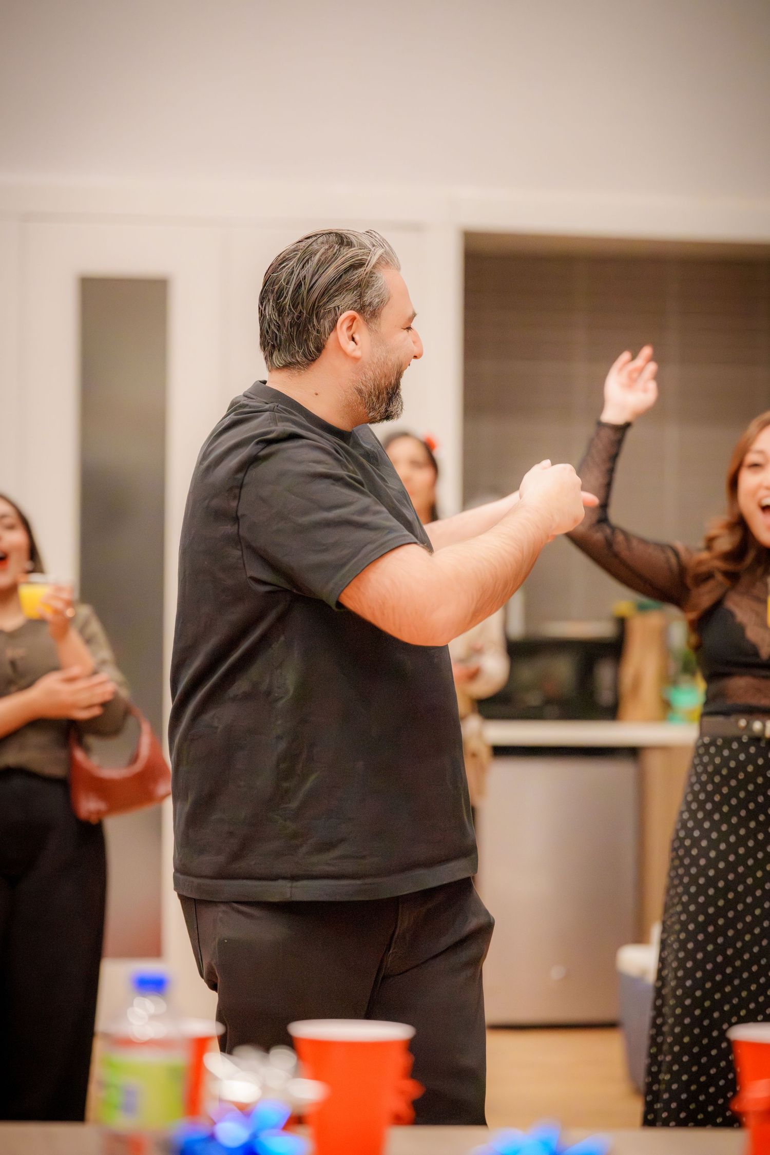 People enjoying a social gathering with red cups and animated gestures in an indoor setting.