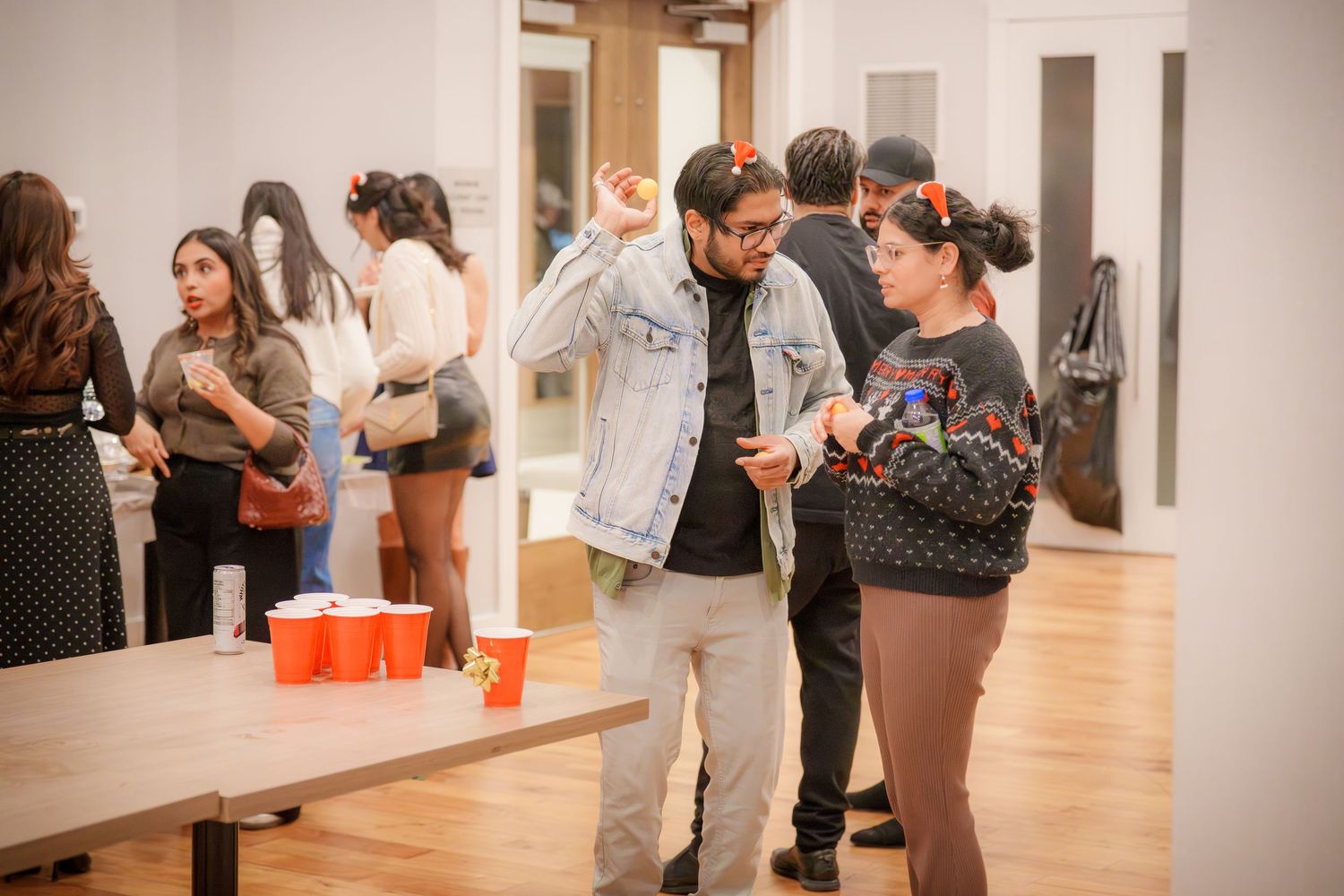 People socializing and holding drinks at an indoor event space.