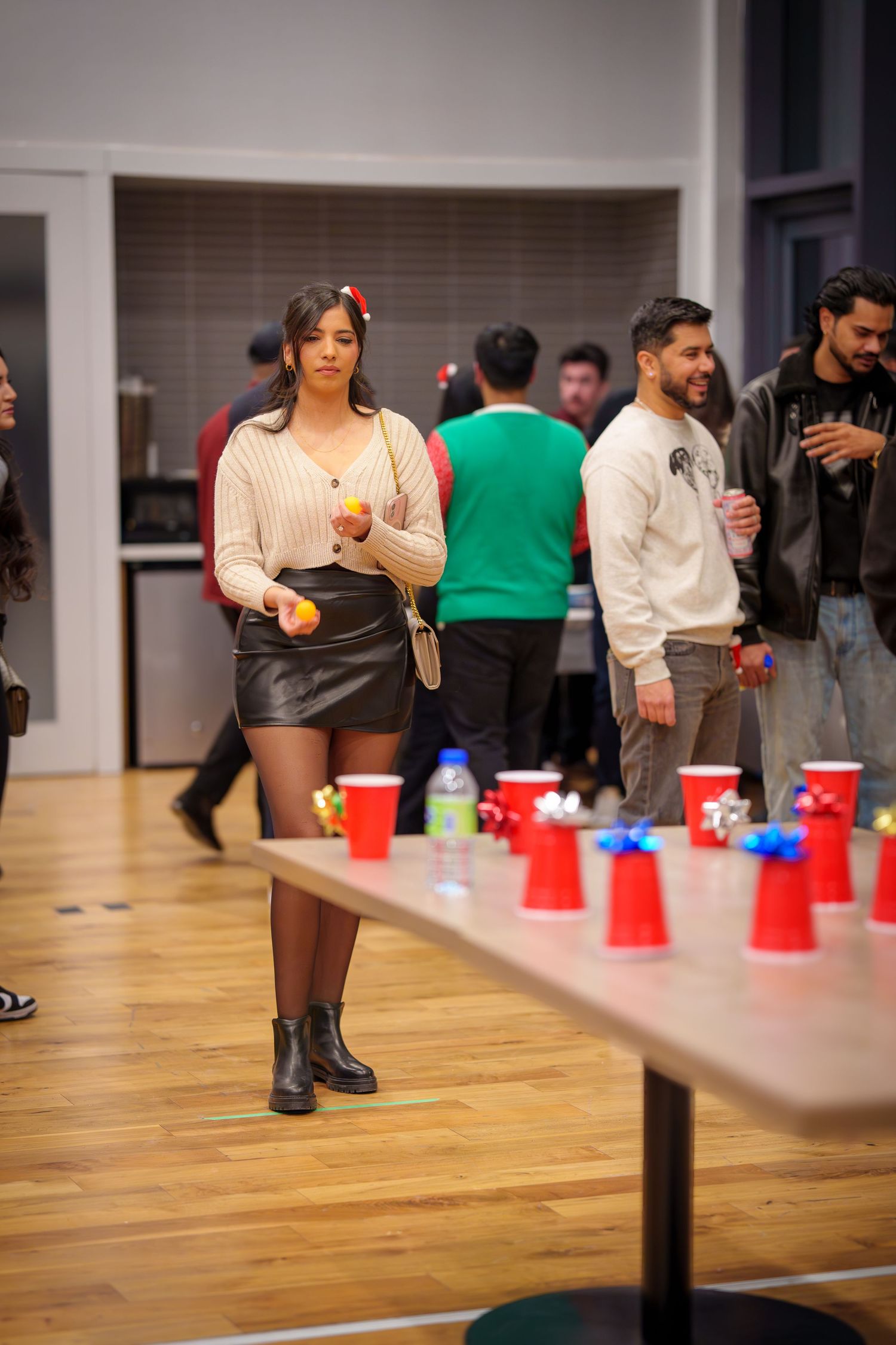 Group playing cup-based party games on hardwood floor with red plastic cups.