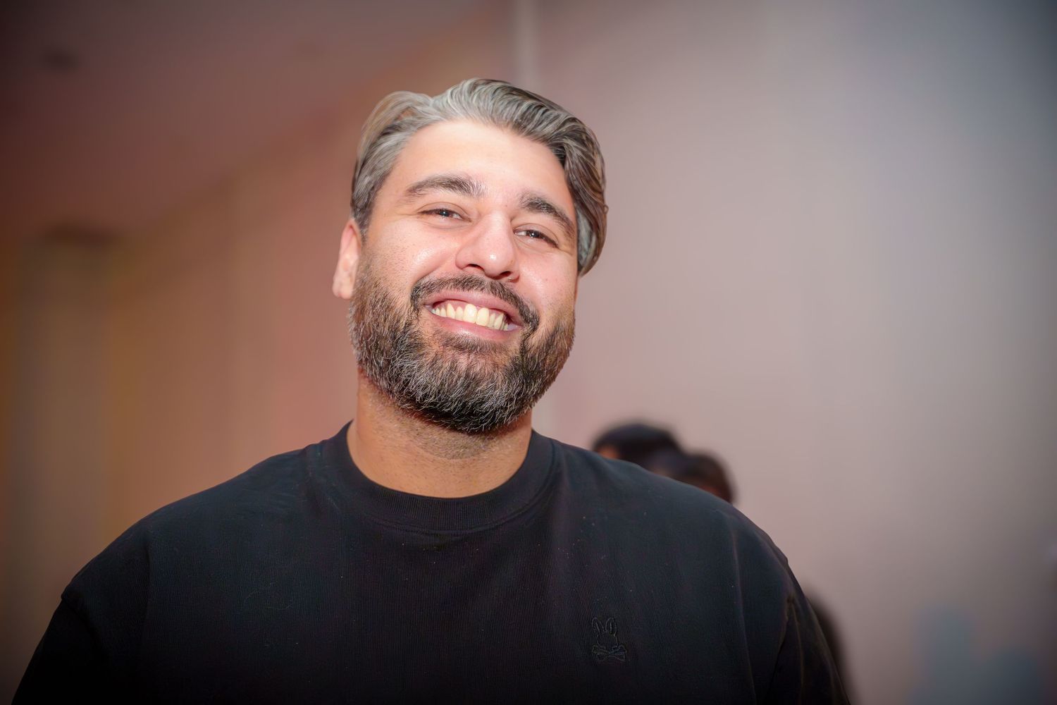 A person smiles warmly during an indoor celebration event.