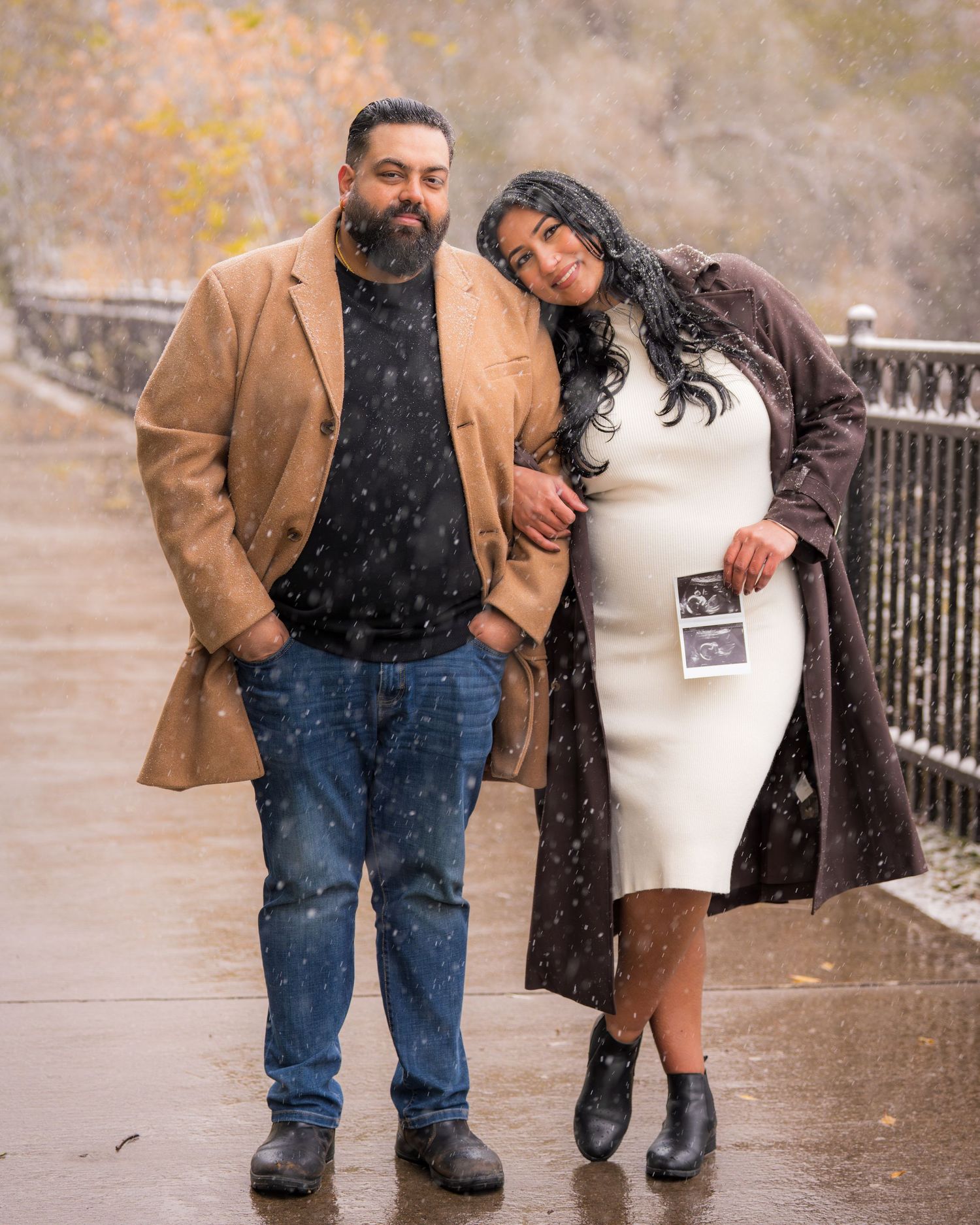 Couple walking together in snowy weather while looking at photographs.