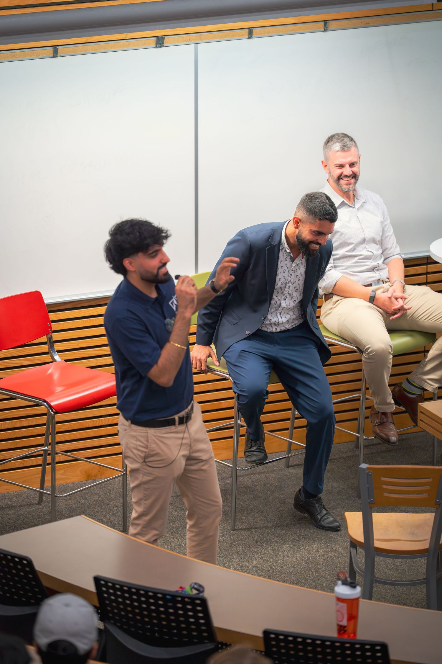 Panel participants seated on wooden benches share a lighthearted moment during discussion.