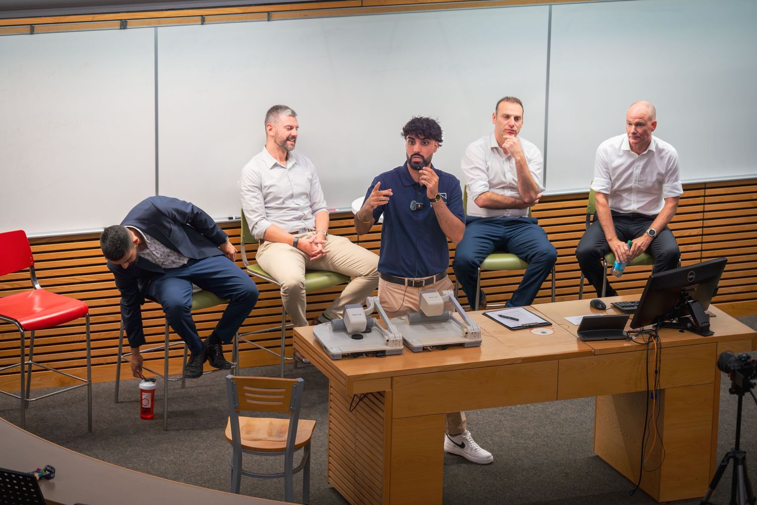 Panoramic view of a modern lecture hall with wooden seating and multiple attendees.