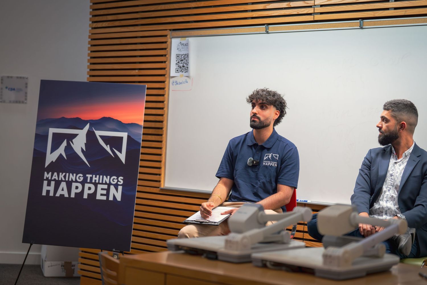 Speakers seated in front of mountain logo banner during professional event.
