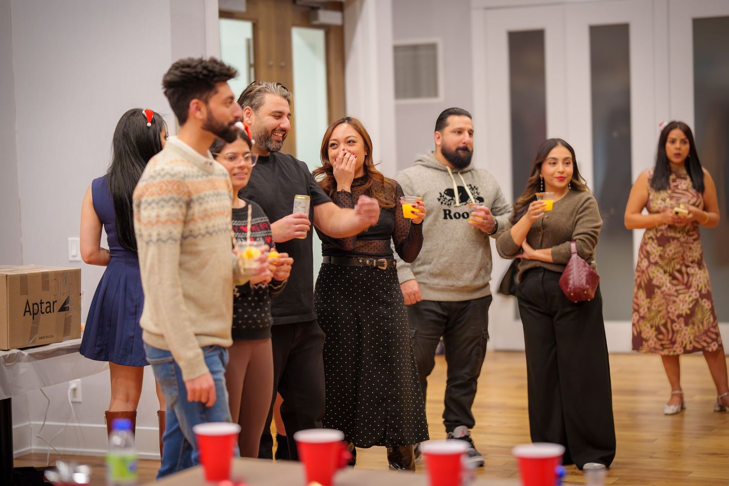 People gathered around red cups set up for beer pong game at indoor party.