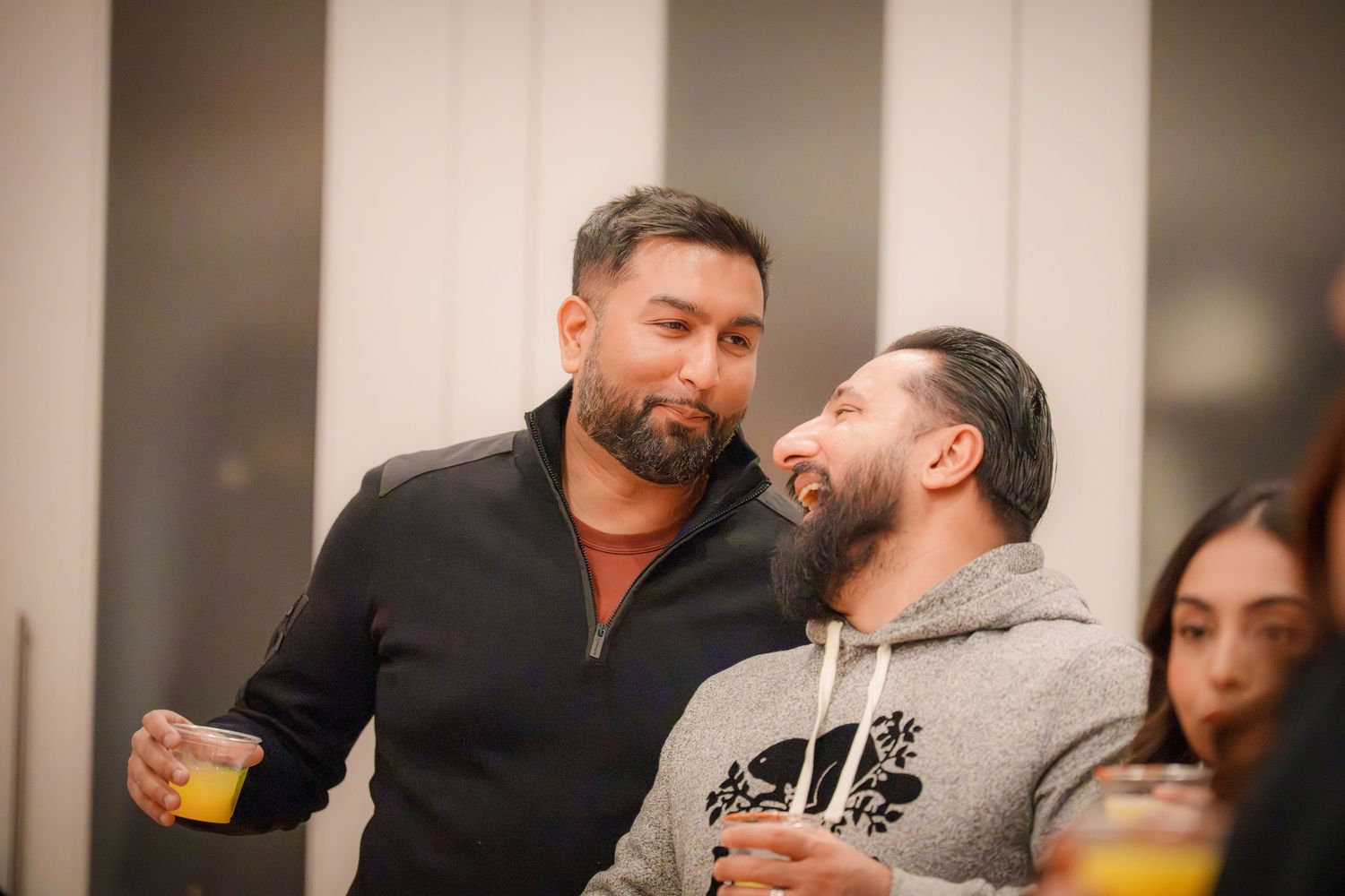Group socializing and laughing together at an indoor holiday gathering.