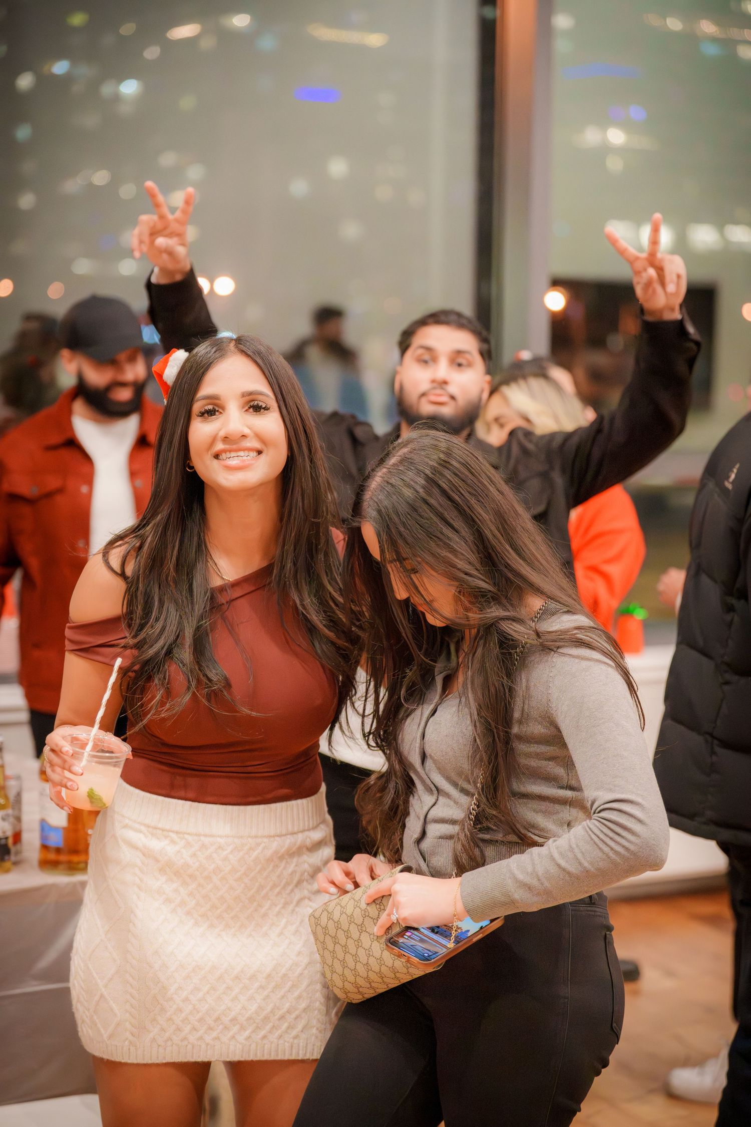 A lively indoor party scene with people in casual attire enjoying drinks and conversation.