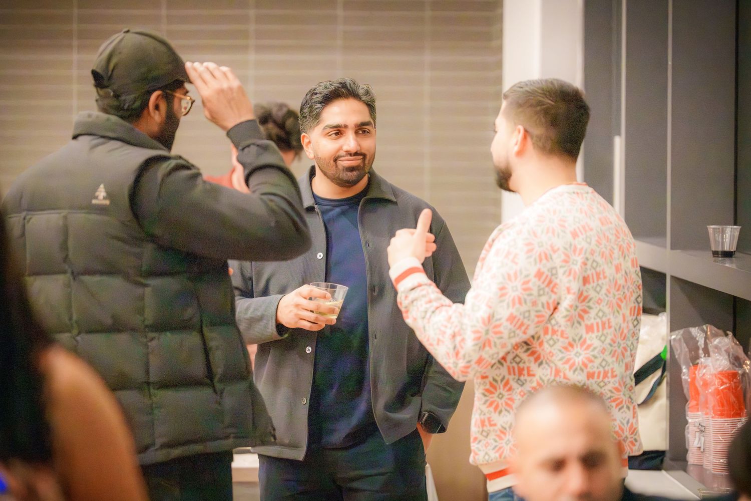 People mingling at indoor party with casual winter attire.