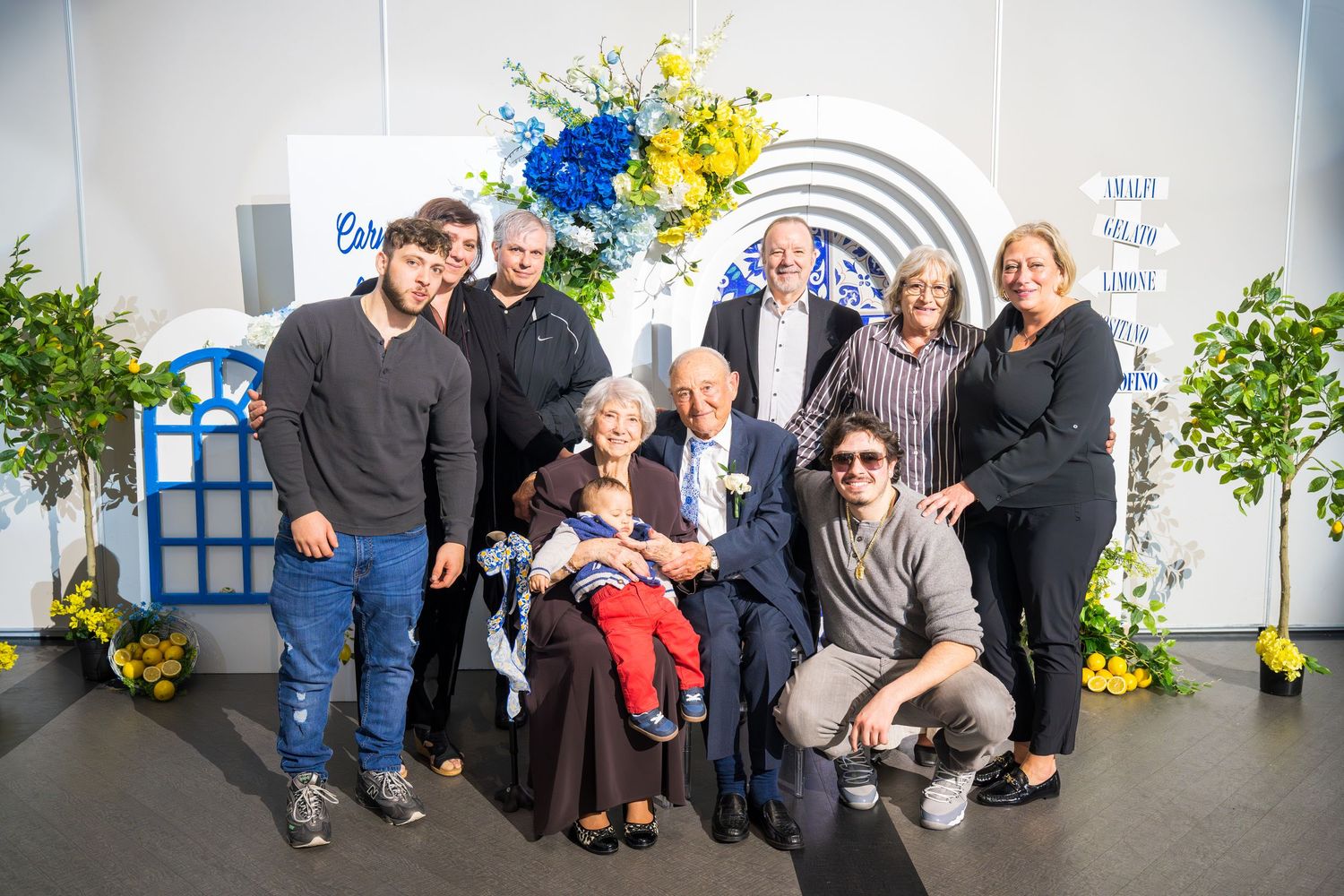 Family group portrait posing together at a festive celebration with floral decorations.