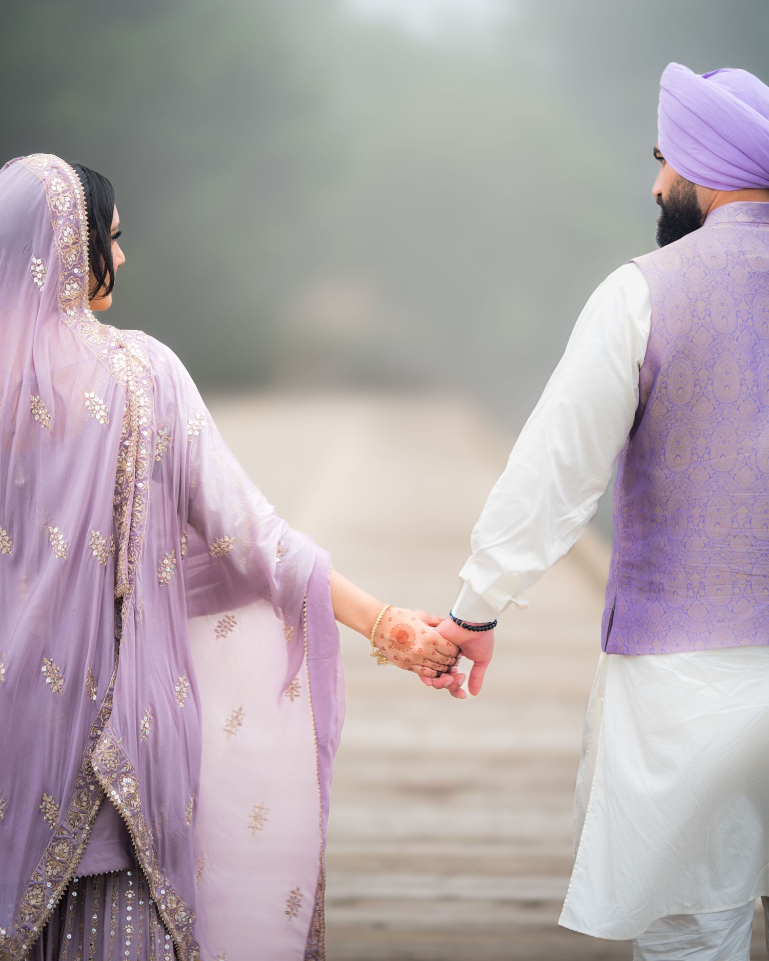 Side view of couple in matching purple and white outfits walking together outdoors.
