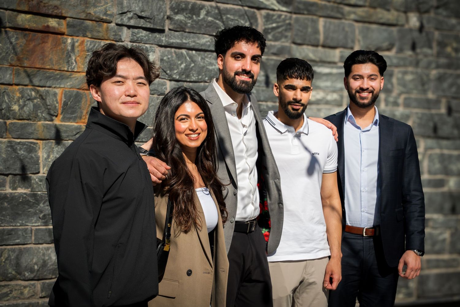 Group photo of speakers against stone wall backdrop.