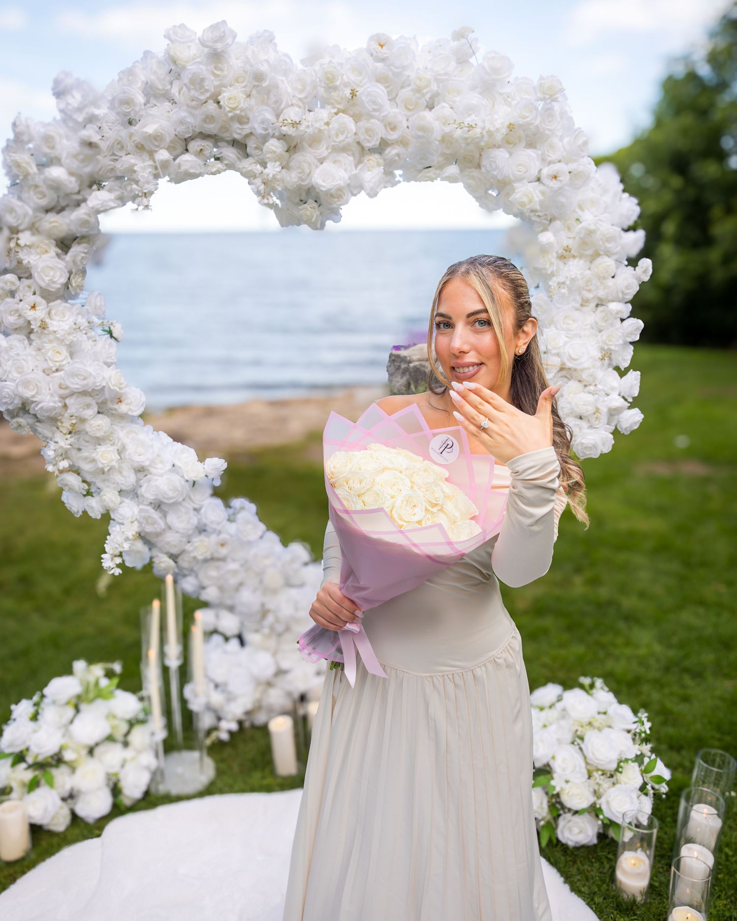 A beautiful proposal setup with a heart-shaped floral arch against an ocean backdrop.