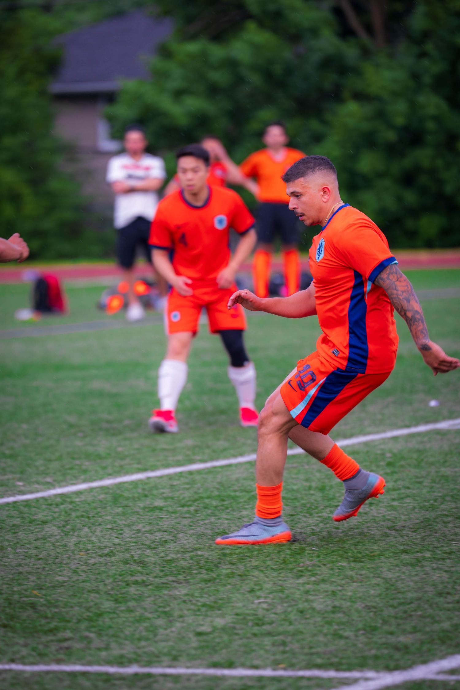 Soccer athlete in orange uniform practicing jumping drills during training.