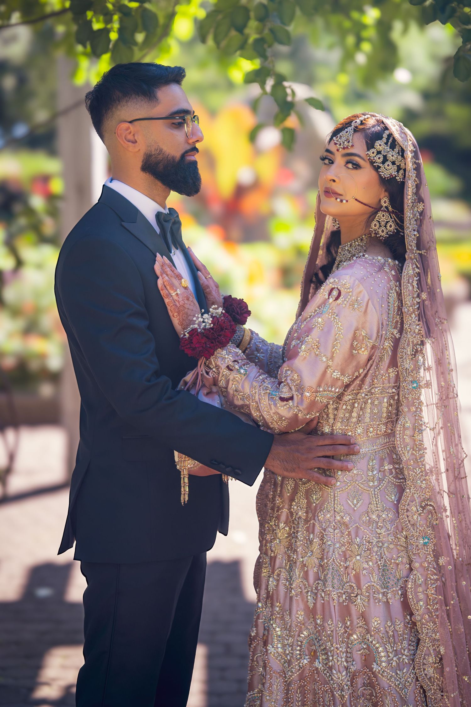 Romantic wedding portrait of couple in traditional South Asian attire embracing outdoors.