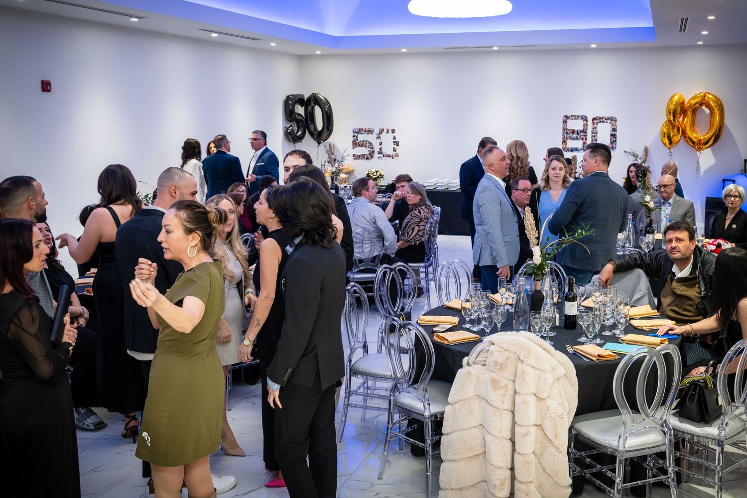 Business networking event with people mingling and socializing in a modern office space with blue lighting.