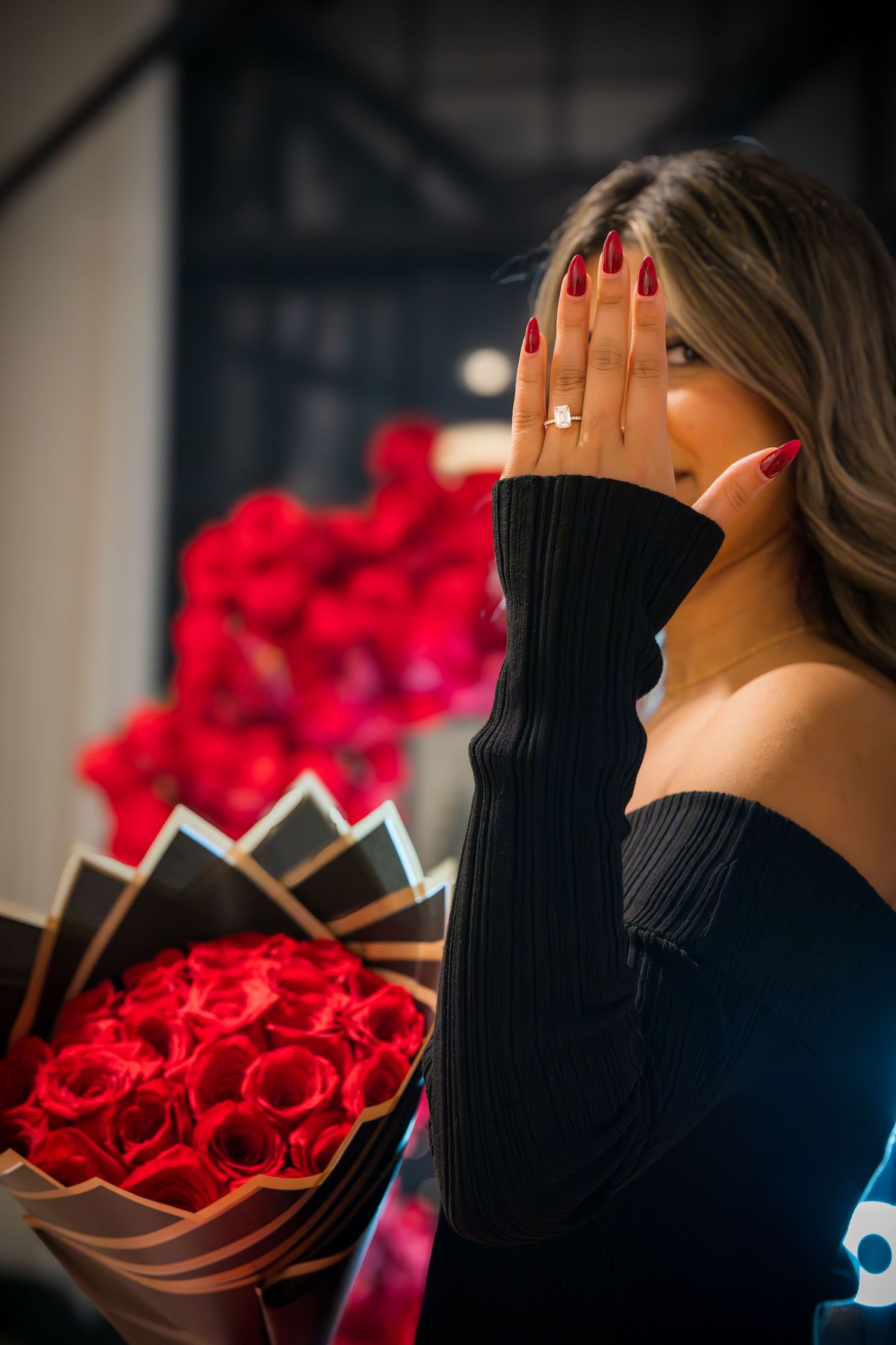 Side profile shot of person in black sweater with red roses in background.
