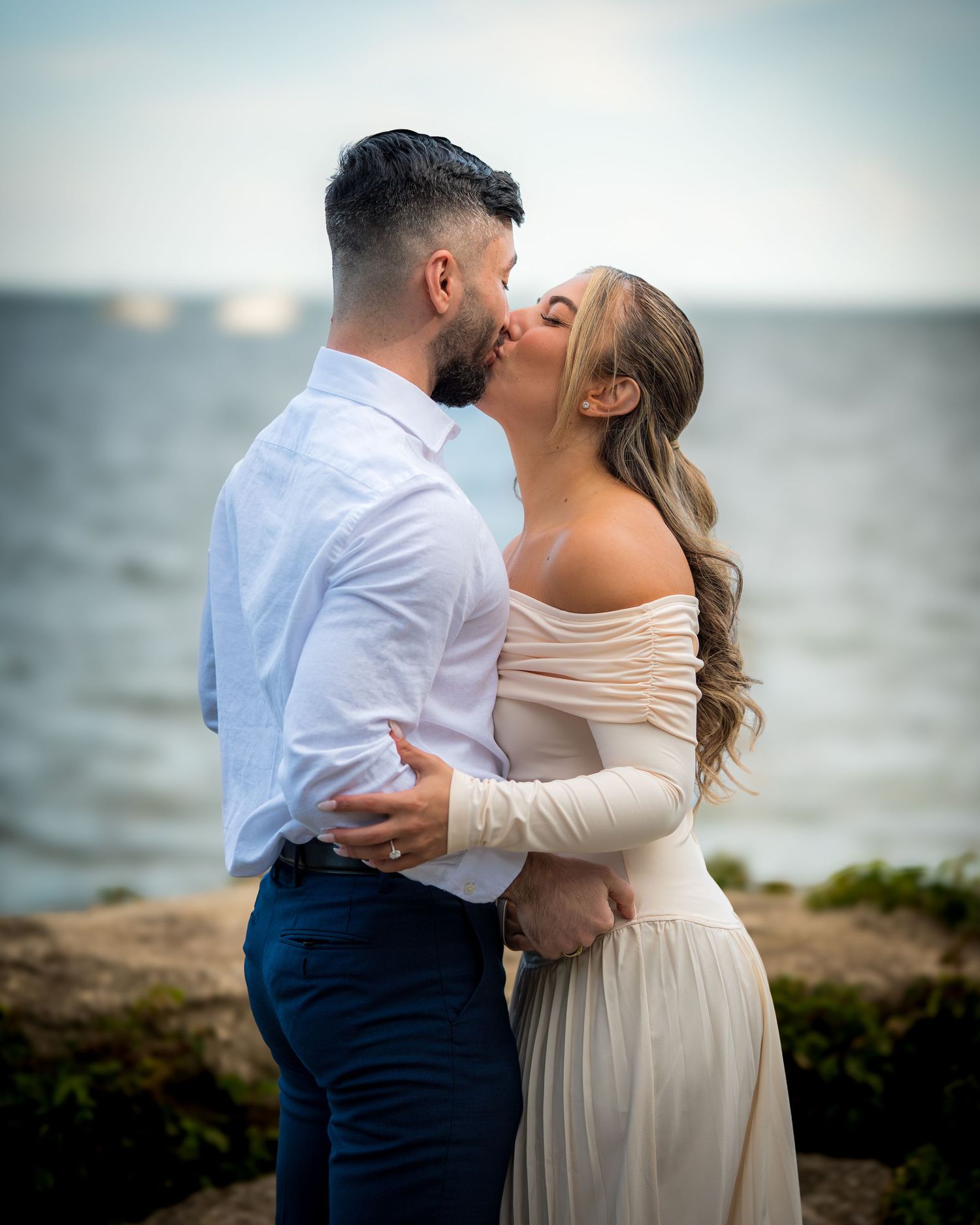Intimate embrace captured during sunset proposal by the water.