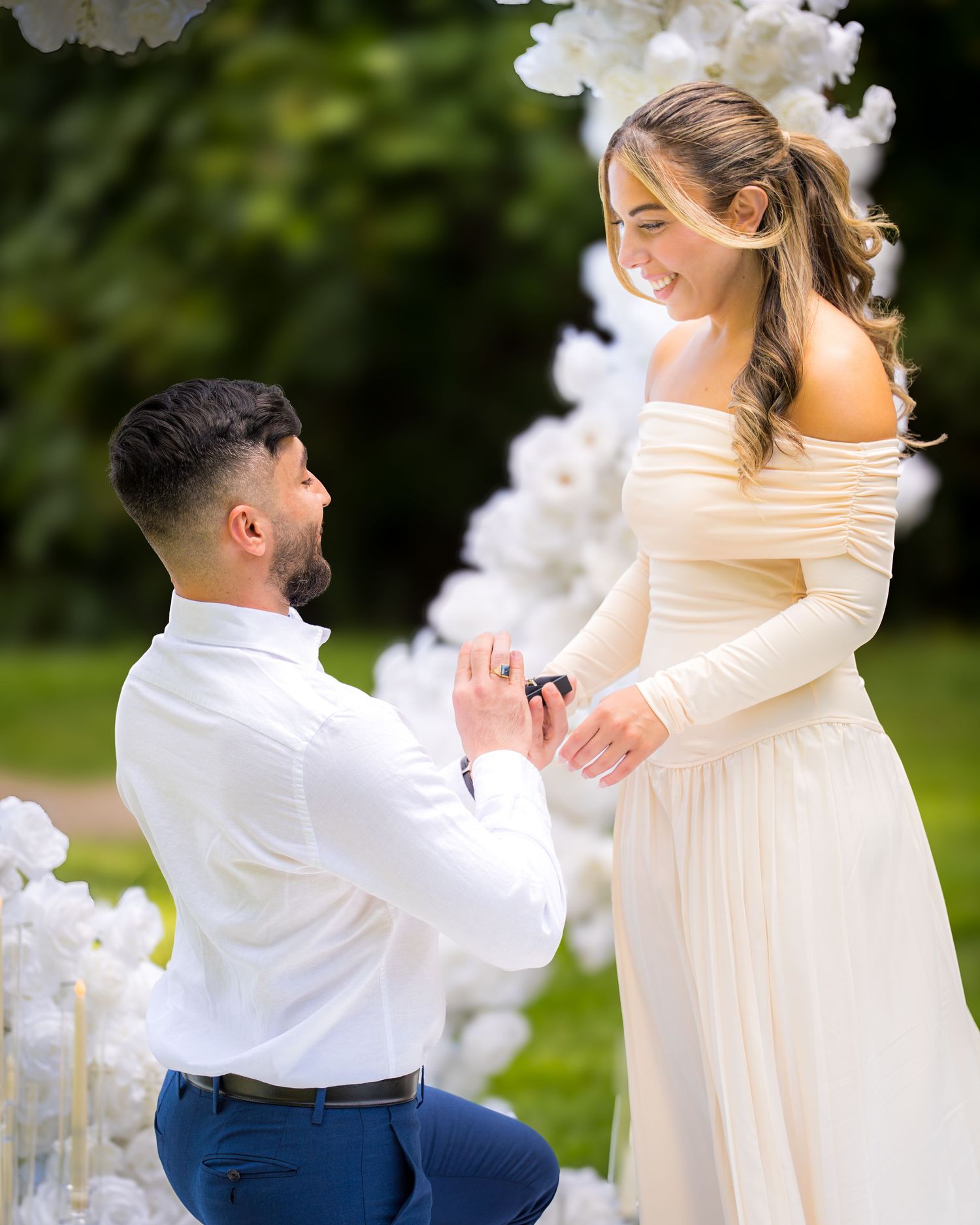 A romantic outdoor wedding dance moment beneath a luxurious white floral arch.