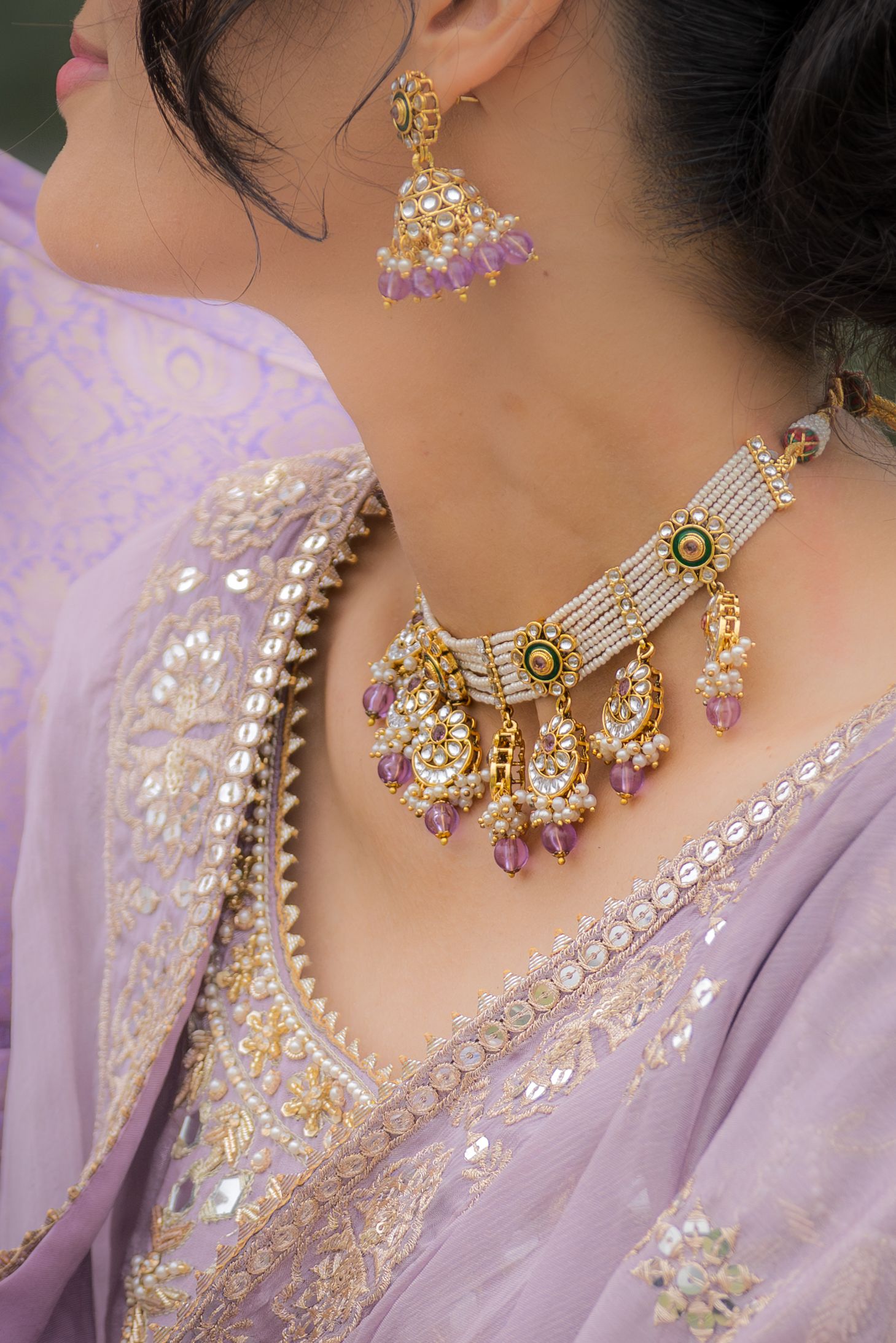 Detailed shots of intricate gold and pearl necklace set against light purple traditional dress.