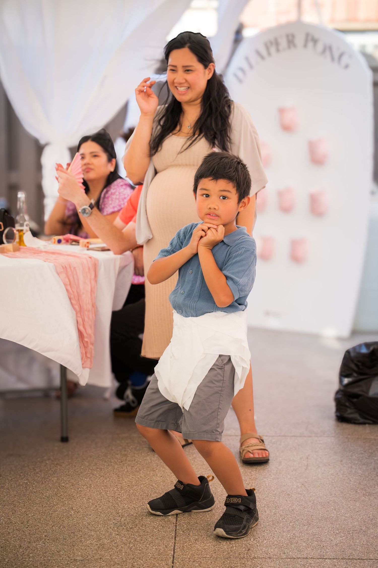 A mother and child dance together in a white-draped event space with pink accents.