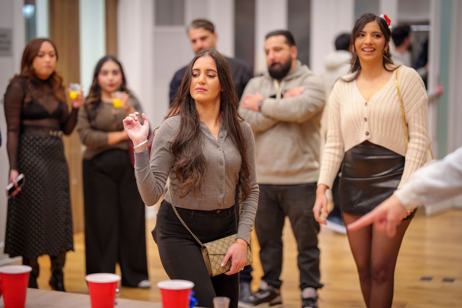 People mingling at indoor event with white walls and wooden floors.