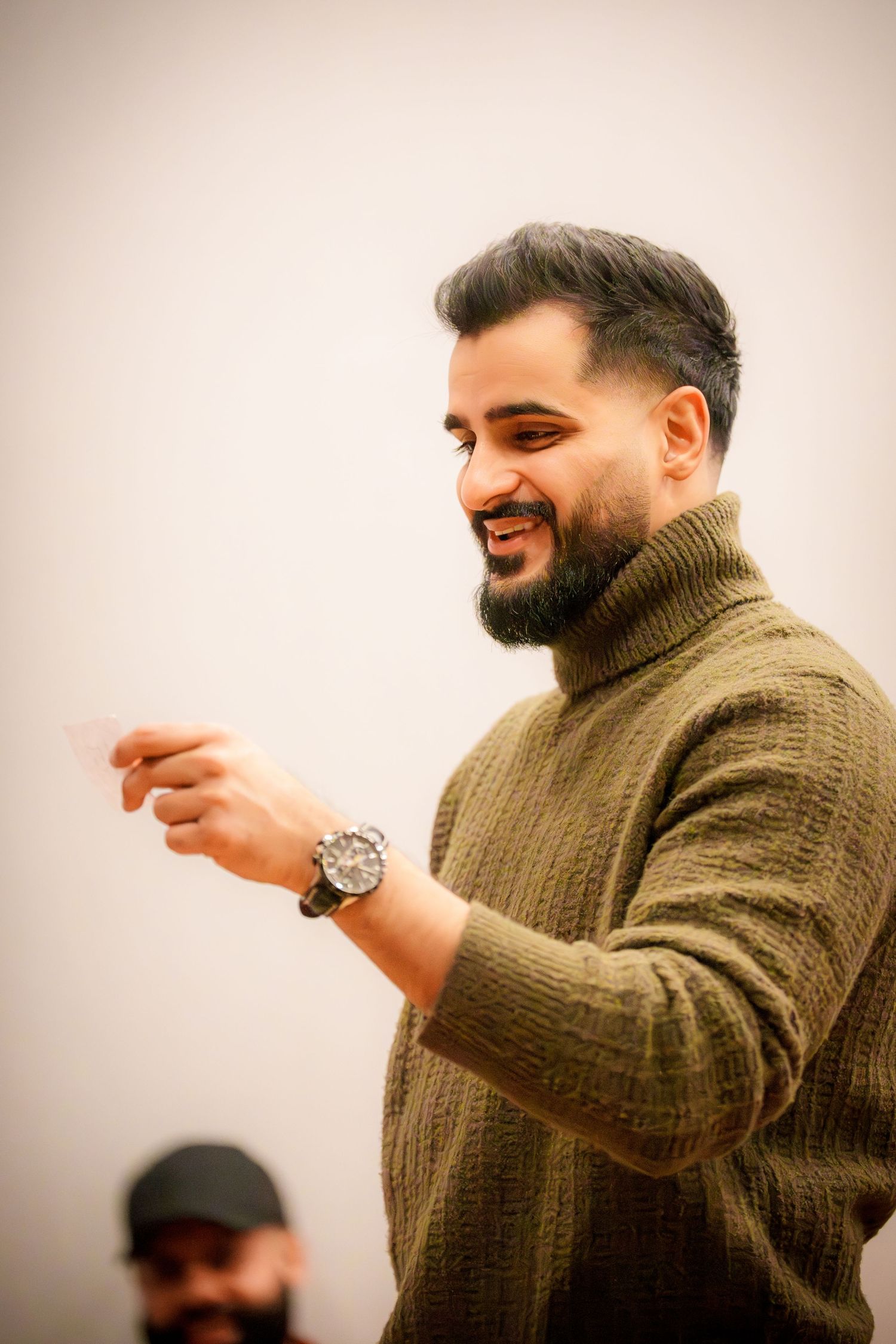 Person in brown sweater gestures animatedly during indoor celebration.