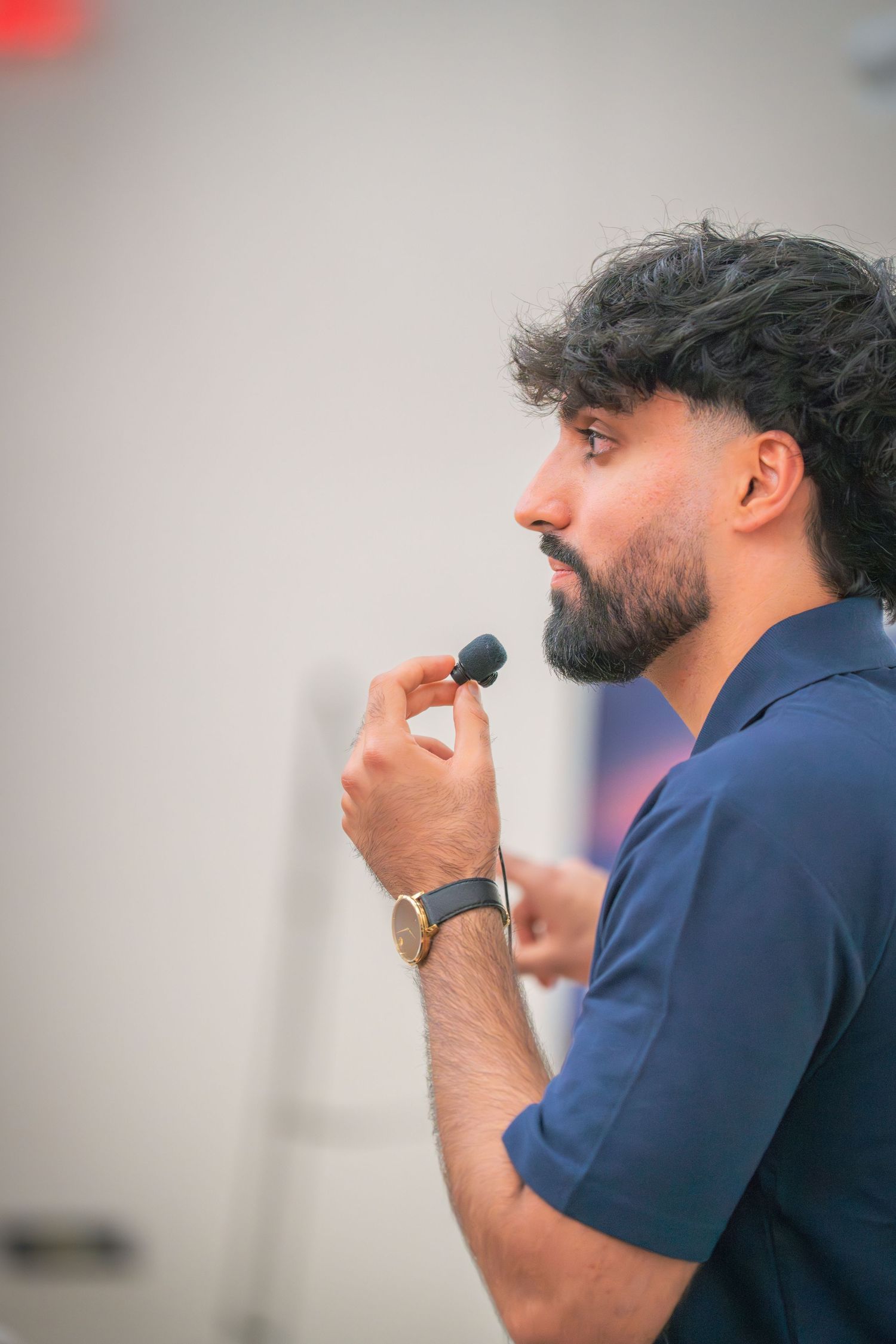 Side profile view of a speaker during a professional presentation in a conference setting.