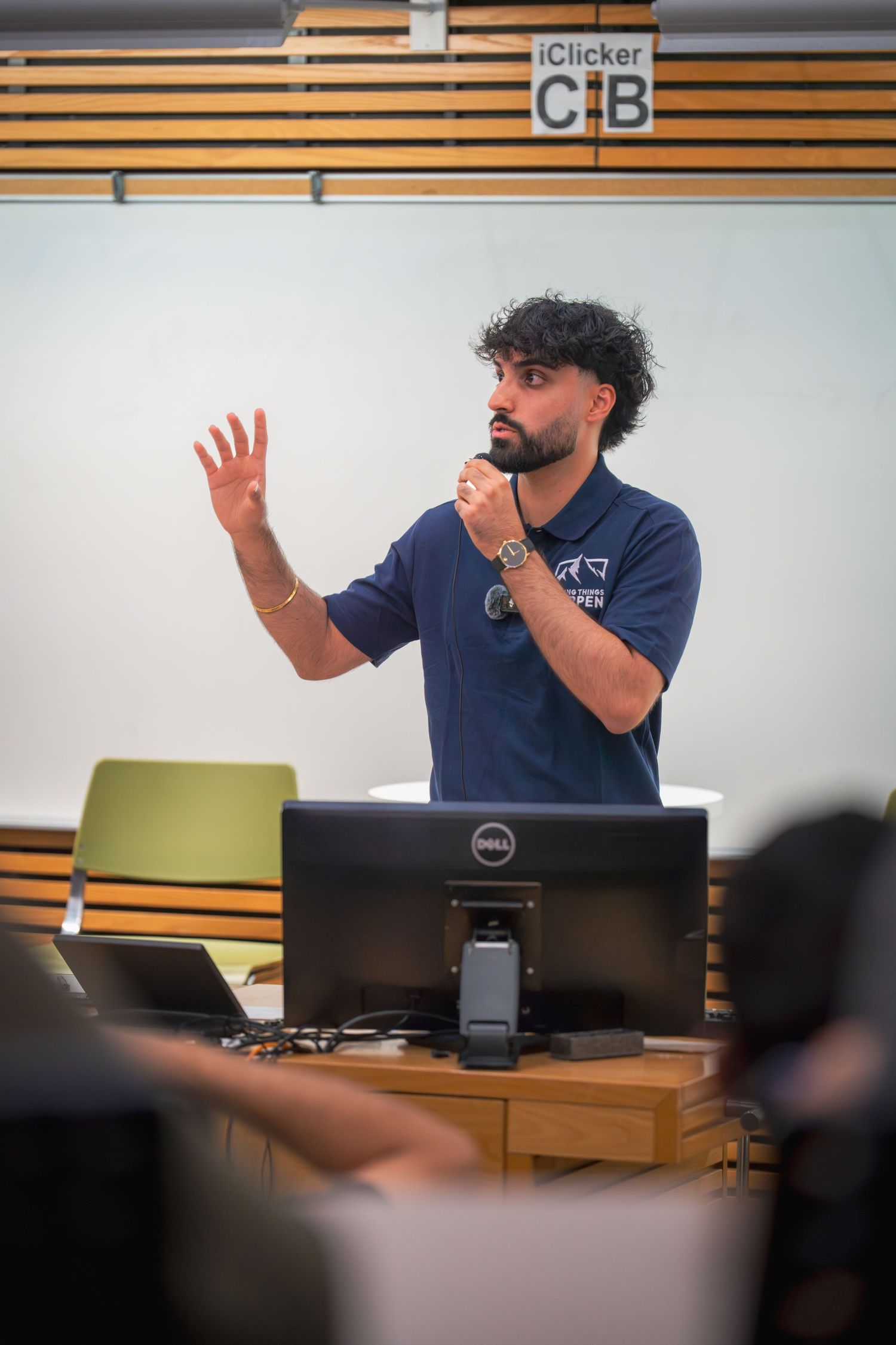Person presenting at a business meeting with a laptop and wooden wall panels in the background.