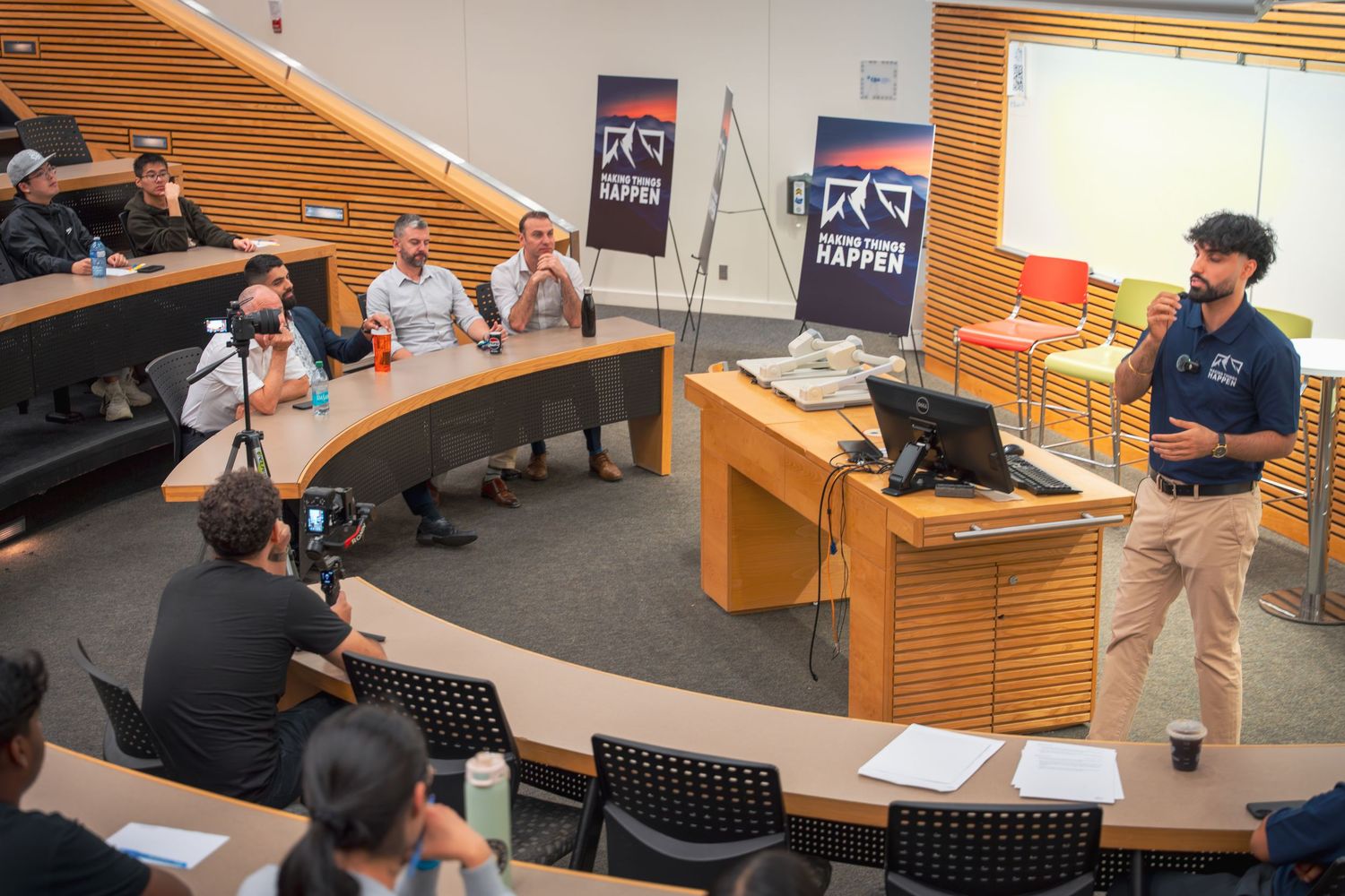 Students participate in a classroom discussion while seated at tables in a modern educational setting.