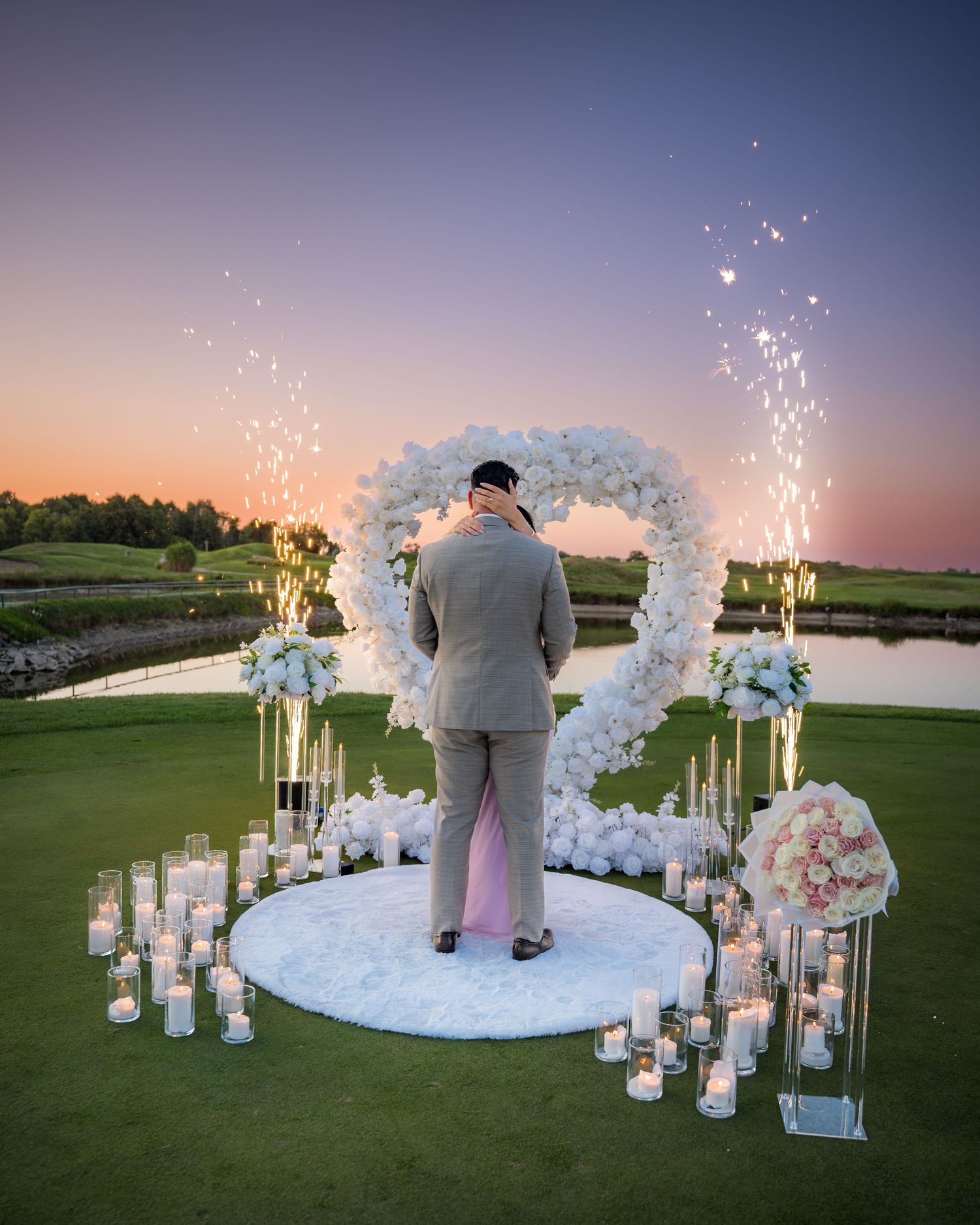 Intimate moment captured during sunset proposal under decorated arch with sparklers.