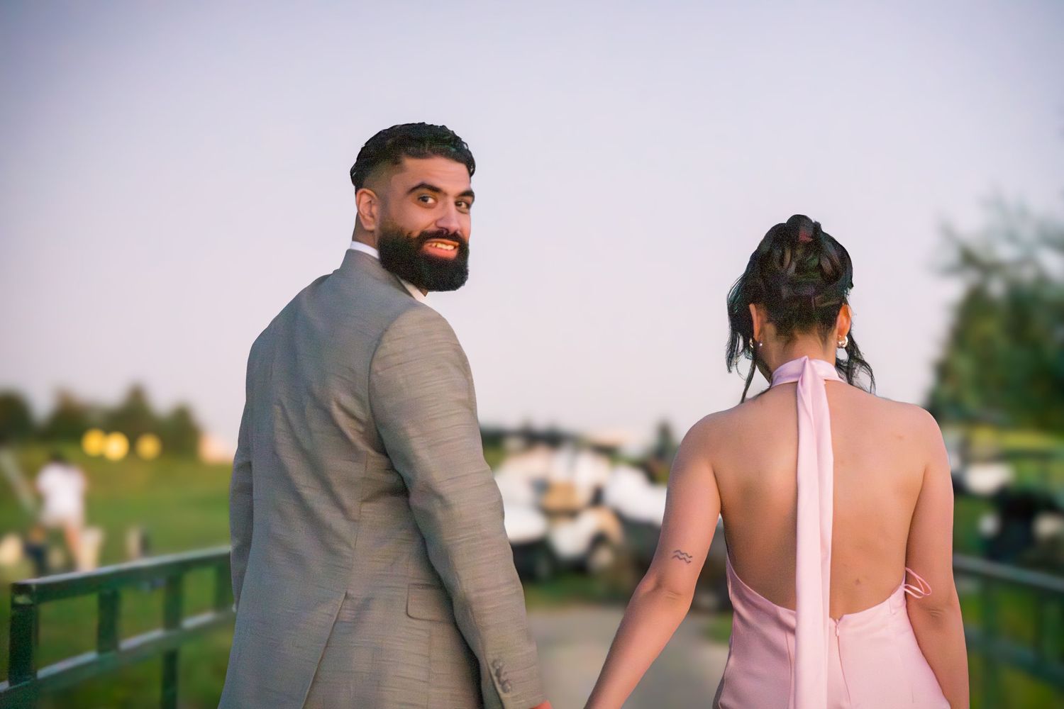 Couple in formal wear walking outdoors during sunset photo session.