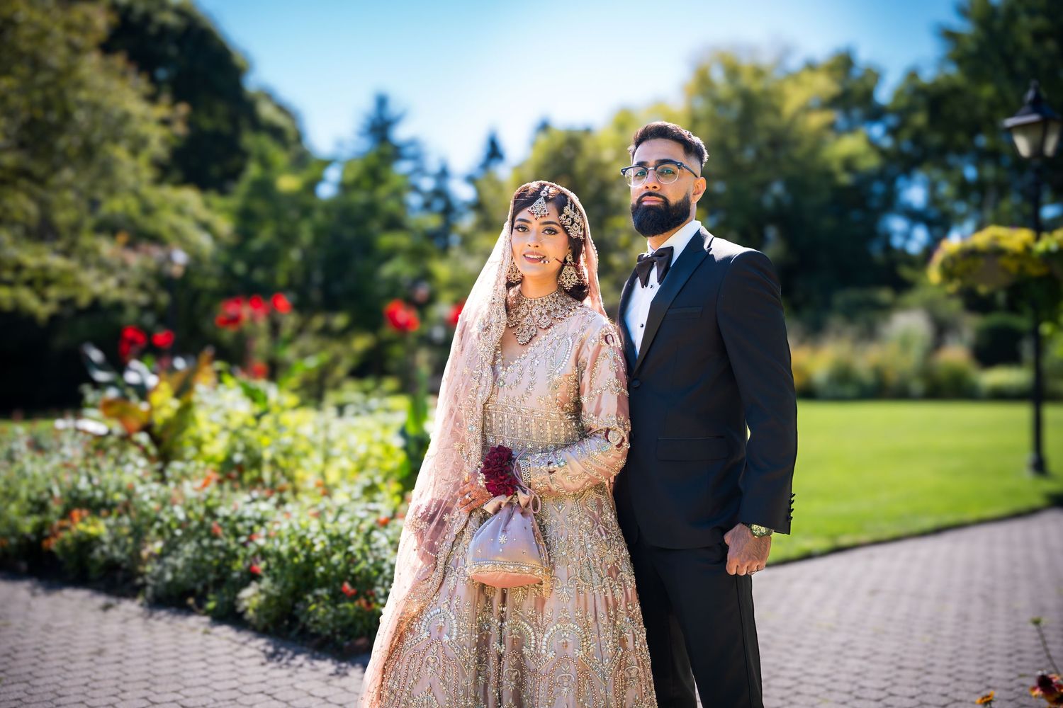 A couple poses in a garden setting during a wedding photo session with colorful flowers in the background.