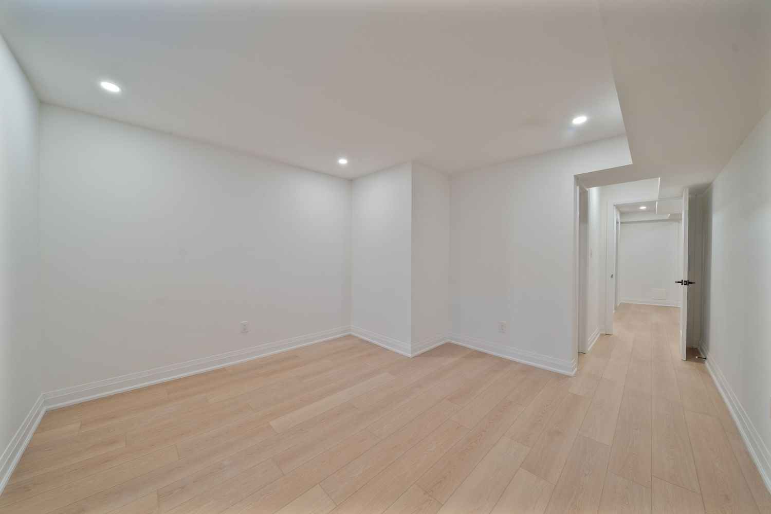 Modern white hallway with light wood flooring, recessed lighting, and clean minimalist design features.