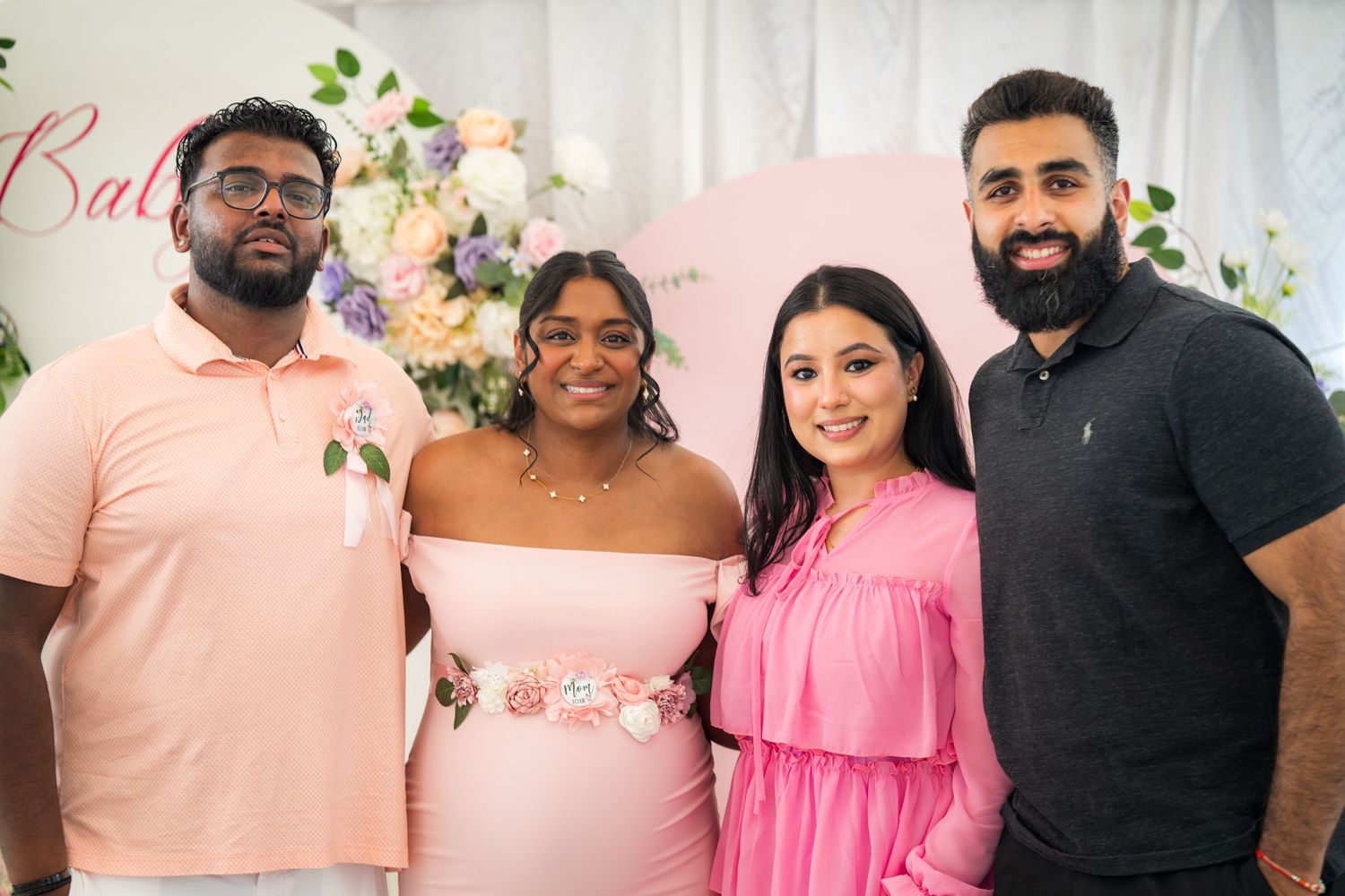 Group photo of party guests wearing coordinated pink and white outfits at a celebration.