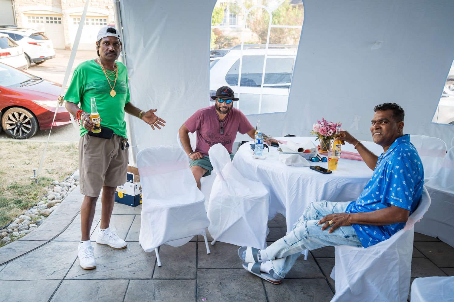 Casual outdoor gathering with drinks and conversation under a white tent.