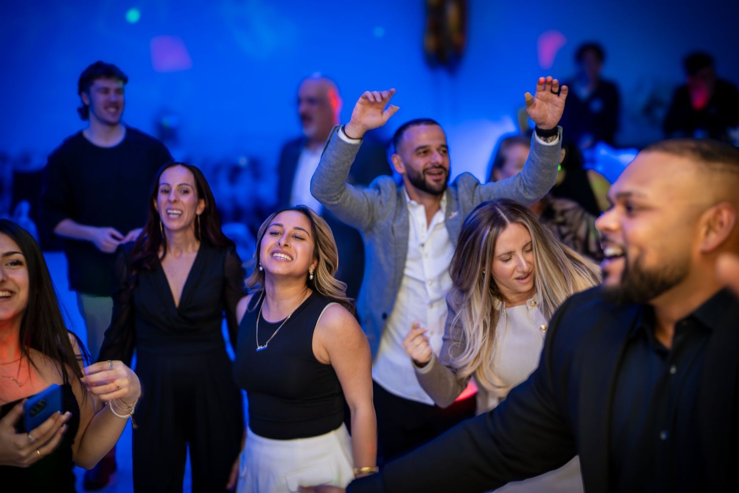 Lively dance party scene with people celebrating under blue ambient lighting.