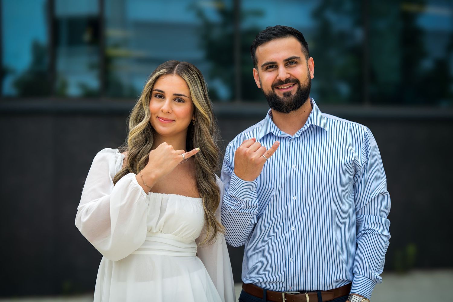 A couple in coordinated outfits poses for engagement-style photos outdoors.