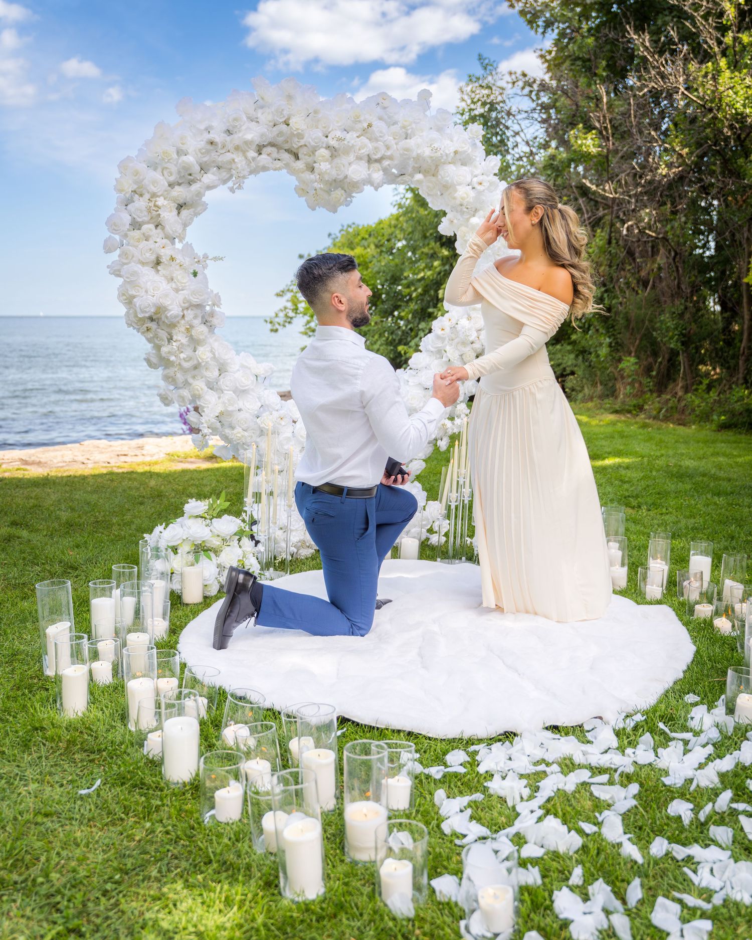 Garden proposal scene decorated with white balloon arch and illuminated candle pathway.