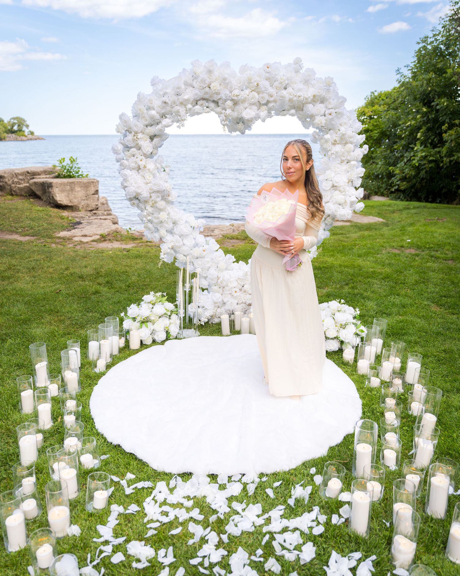 A beautiful proposal scene with white floral arch and candles surrounding a circular platform.