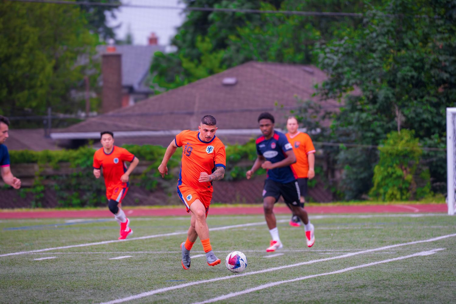 Players chase after the ball during an intense soccer match on an outdoor field.